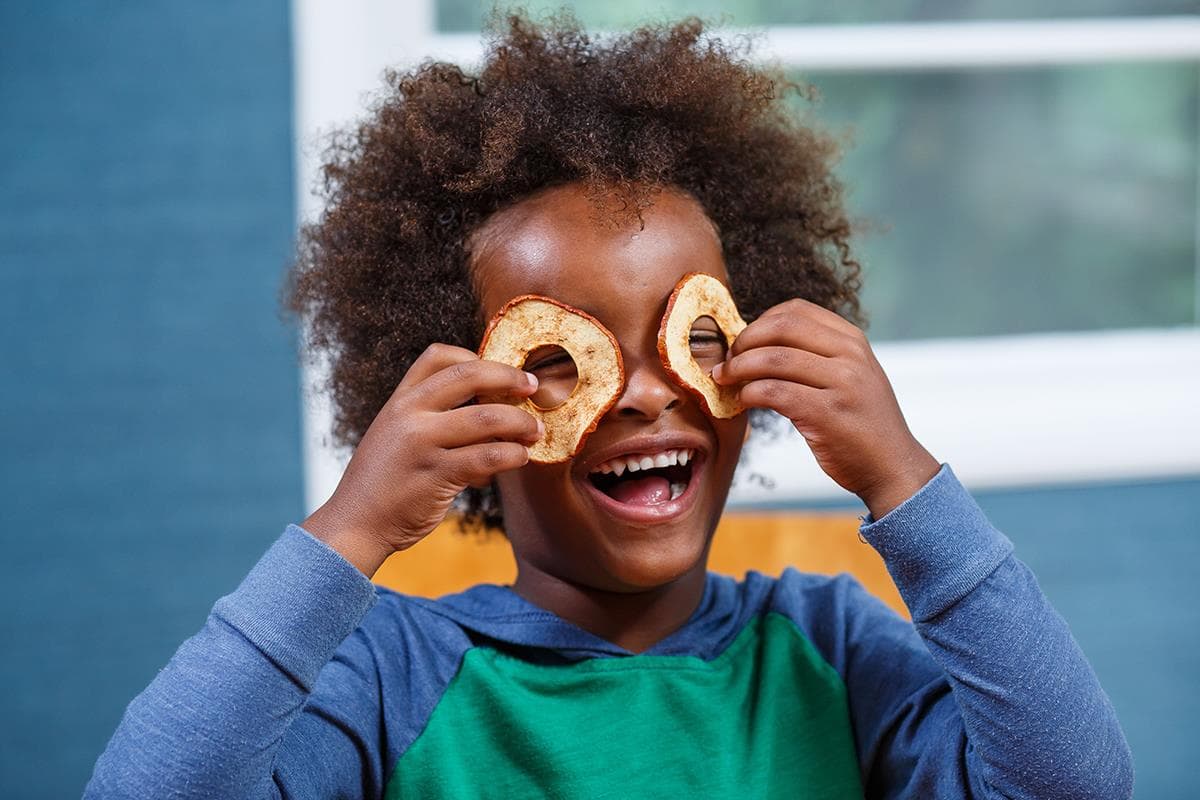 child holding apple rings over eyes